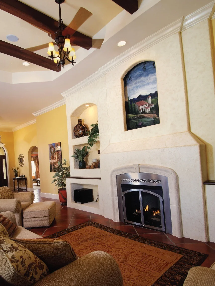 Stone fireplace surround with arched niches, wood beam ceiling, and recessed lighting in living room