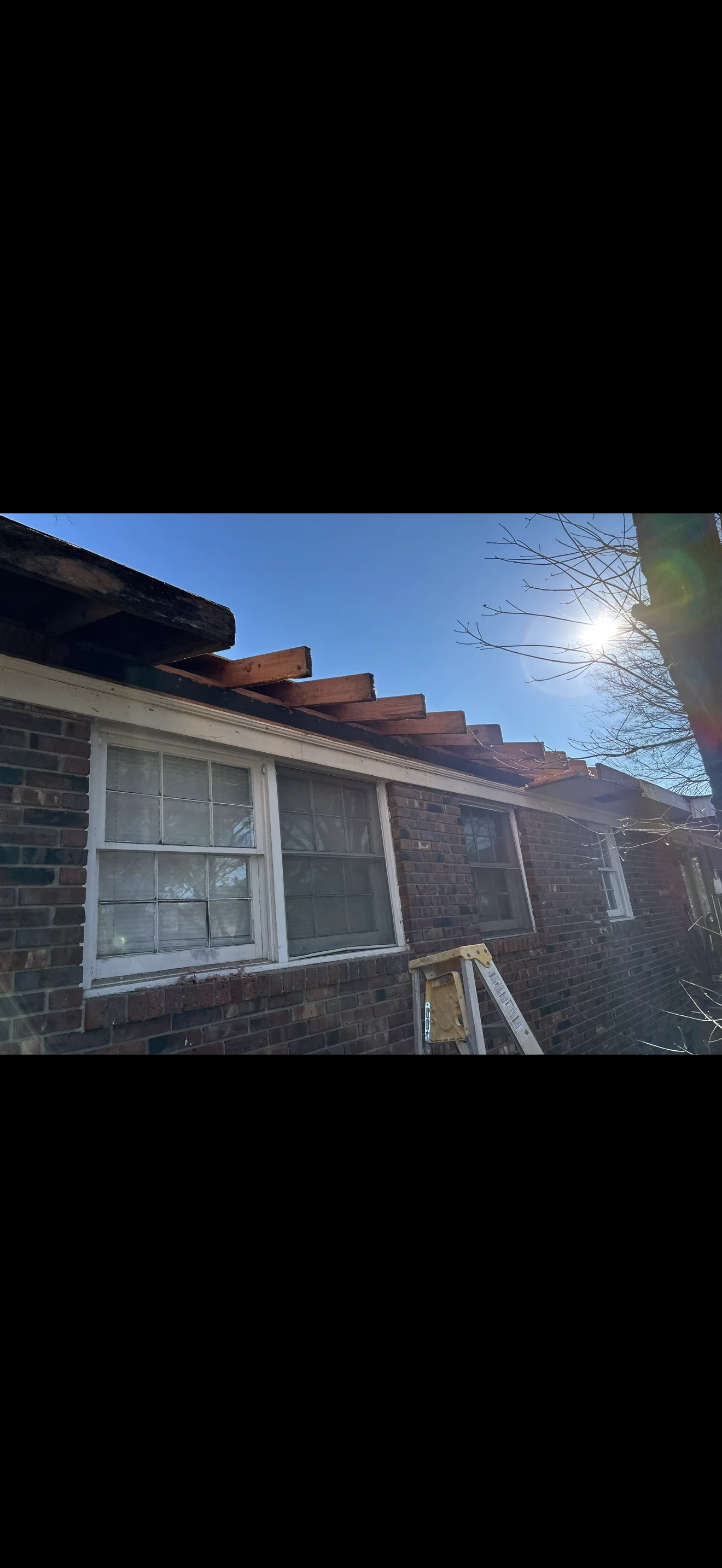 White-framed casement windows installed on brick residential exterior with wooden eaves